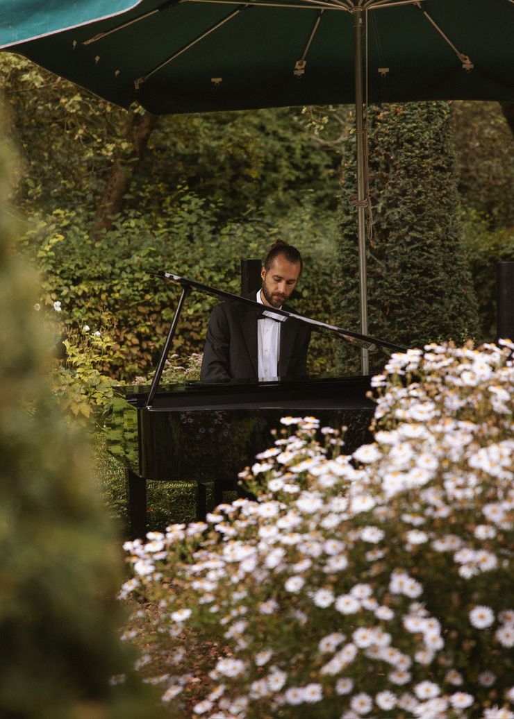 Arian M&uuml;ller performing on grand piano in a flower garden