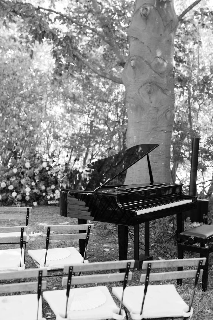Grand piano set up outdoors under a tree before a ceremony